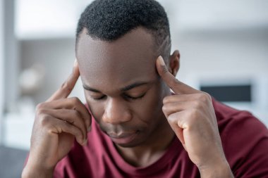 Esmer tenli genç bir adam baş ağrısı çekiyor.