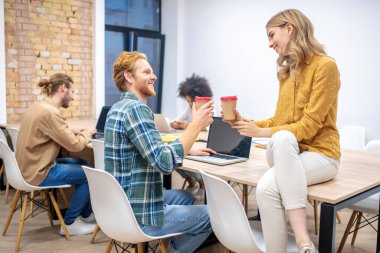 Kızıl adam ofiste sarışın bir iş arkadaşıyla konuşuyor.