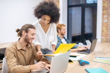 Kıvırcık saçlı mulatta erkek arkadaşına bir şey gösteriyor.