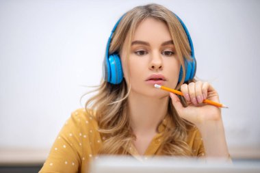 Kulaklıklı sarışın güzel kız masada oturuyor ve dikkatlice dinliyor.