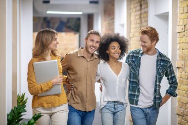 Group of smiling young people walking in the corridor and talking