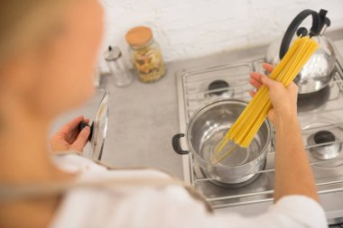 Ev hanımı sosisin içine spagetti koyuyor.