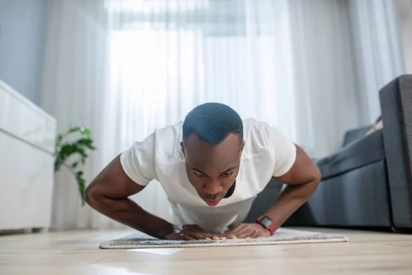 Afrikanisch amerikanisch guy in weiß clothes having ahome workout — Stockfoto