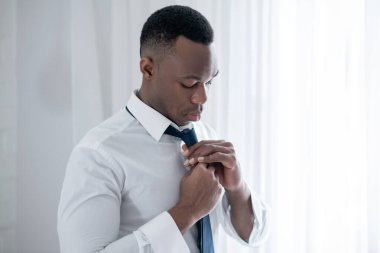 Genç bir Afrikalı Amerikalı kravat takıyor ve şık görünüyor.