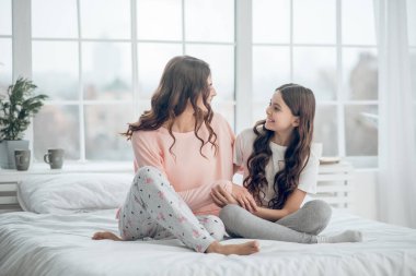 Anne ve kızı pijamalarıyla yatakta oturuyorlar.