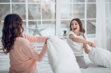 Kız ve anne yastık dövüyorlar.