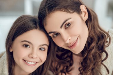 Gülümseyen anne ve kızının yüzünü kapat.