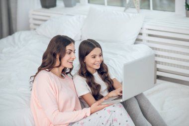 Anne ve kızı sevinçle dizüstü bilgisayara bakıyor.