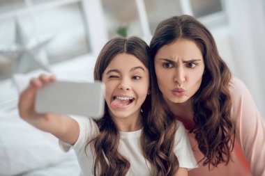 Annesinin selfie çekerken yüzünü buruşturan komik kız.