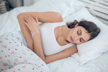 Gözleri kapalı bir kadın yatakta yatıyor.