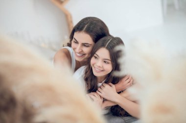 Sevgi dolu anne ve kız yanyana sarılıyorlar.