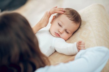 Anne usulca uyuyan küçük çocuğa dokunuyor