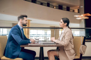 Bej takım elbiseli genç bir kadın müdürle röportaj yapıyor.