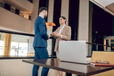 Zarif takım elbiseli kadın ve erkek iş merkezinin korrojunda konuşuyor.