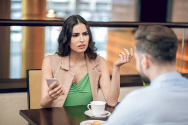 Genç bir kadın bir erkekle konuşuyor ve hayal kırıklığına uğramış görünüyor.