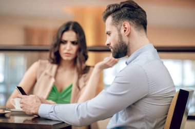 Kadın ve erkek restoranda oturuyor ve mutsuz görünüyorlar.