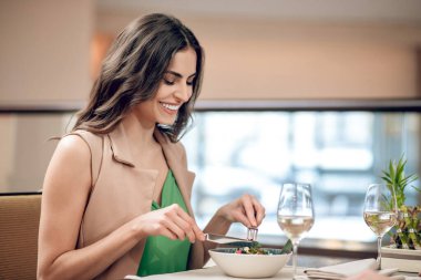 Koyu saçlı kadın yemeğini restoranda yiyor.