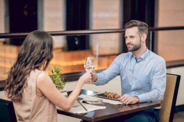 Resaurant 'ta yemek yiyip kadeh kaldıran bir çift.