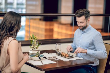 Resaurant Wjile 'da yemek yiyen bir çift karşı karşıya oturuyor.