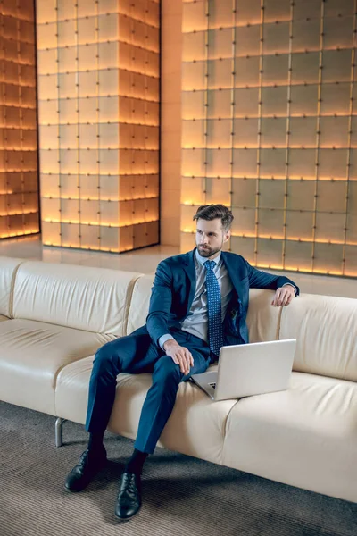 Ofiste oturan takım elbiseli yakışıklı sakallı genç adam.