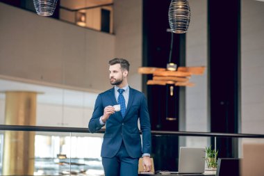 Güzel takım elbiseli şık bir işadamı kahve içiyor.