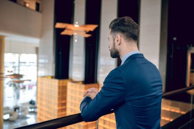 Zarif iş adamı ayakta duruyor ve konsantre görünüyor.