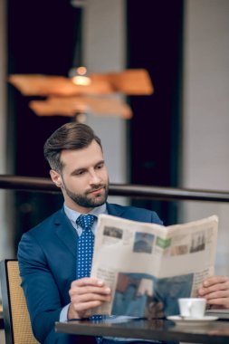 Güzel takım elbiseli şık bir işadamı sabah gazetesini okuyor.