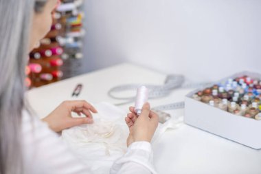 Dikiş dikmek için ışık ipliğini seçen kadın