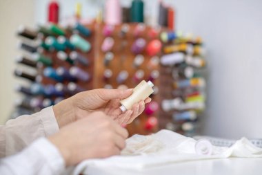 Kadın elleri bej iplikleri tutuyor.