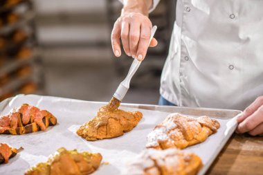 Fırçalı erkek eli kruvasan yüzeyine dokunuyor.