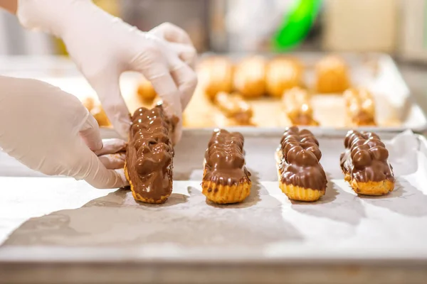 Hände legen sorgfältig fertige Eclairs auf Tablett — Stockfoto