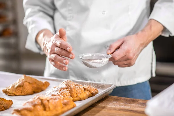 Manos masculinas rociando confitería con azúcar en polvo — Foto de Stock