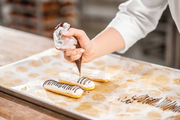 Decoración de la mano eclair con chocolate usando bolsa de pastelería —  Fotos de Stock