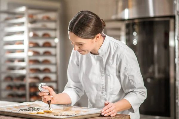 Femme avec sac à pâtisserie sur plateau de gâteaux — Photo