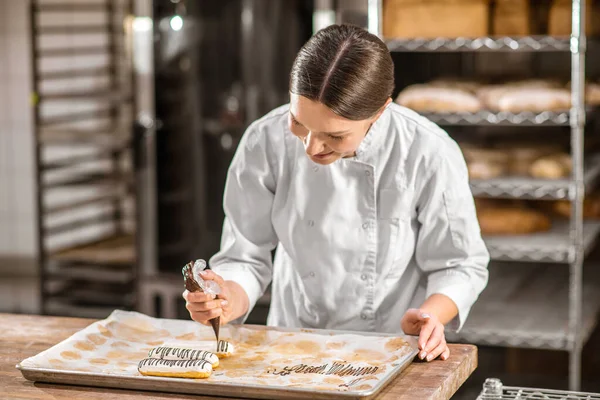 Mujer interesada pastelería chef decoración eclairs —  Fotos de Stock