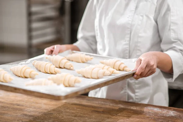 Tangan dengan nampan croissant mentah disiapkan untuk dipanggang — Stok Foto