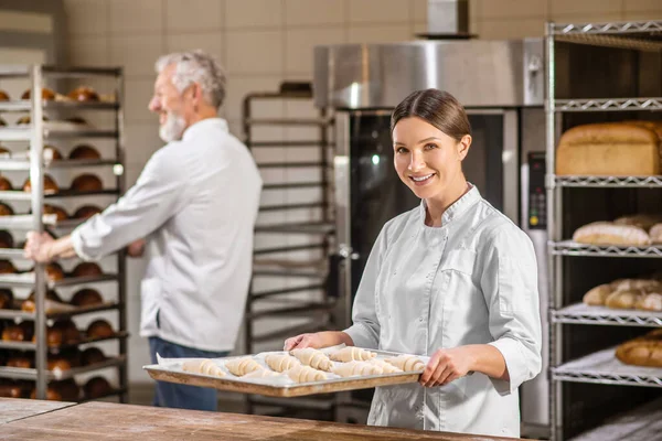 Kvinna med bricka av croissanter man med rack av bröd — Stockfoto