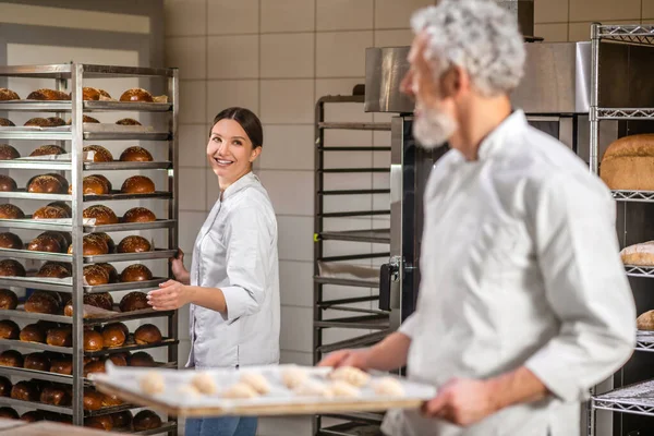 Joyeuse femme près de la grille de petits pains et collègue — Photo