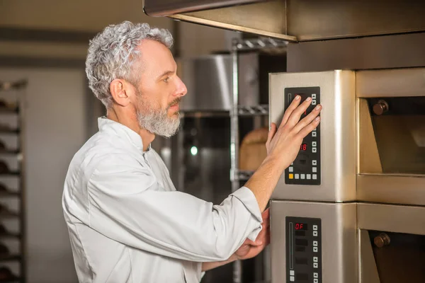 Perfil del hombre serio cerca del panel de control del horno —  Fotos de Stock