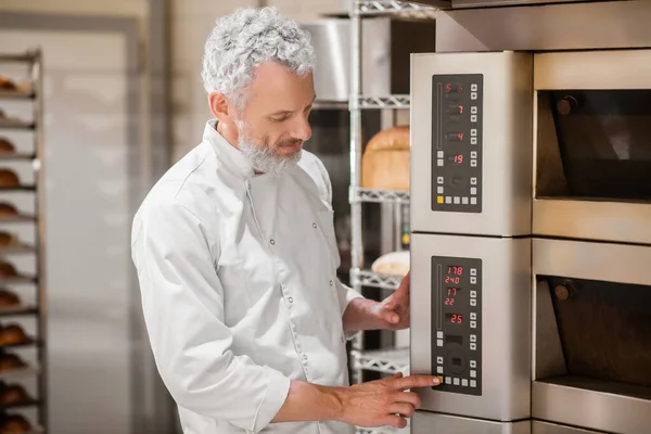 Man touching finger to control panel of oven — Stock Photo, Image