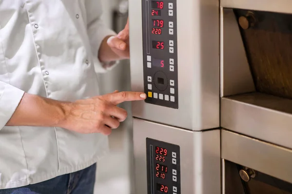 Finger of mans hand touching control button of oven — Stock Photo, Image