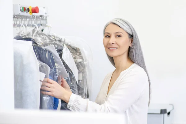 Femme souriante debout près de rack avec des vêtements — Photo