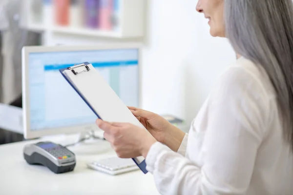 Woman reading document standing behind counter — Stock Photo, Image