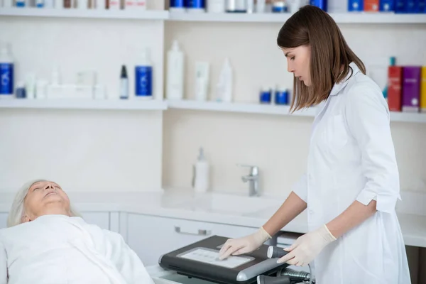 Cosmetologo in mantello bianco che prepara l'apparecchio per le procedure — Foto Stock