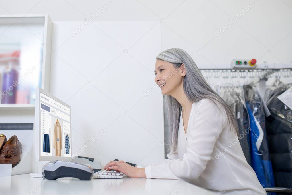 Joyful woman at workplace looking at computer