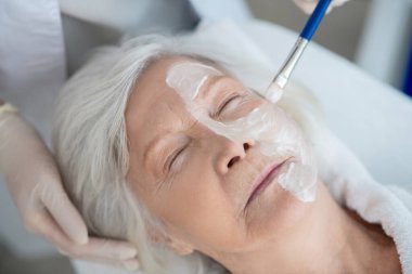 Güzellik uzmanı kadınların yüzüne nemlendirici maske takıyor.