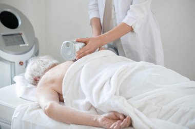 Kadın bir hastaya anti-ostondrosis prosedürleri uygulayan fizyoterapist.