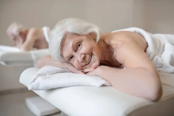 Seniorin liegt auf Sofa im Wellness-Salon und genießt — Stockfoto