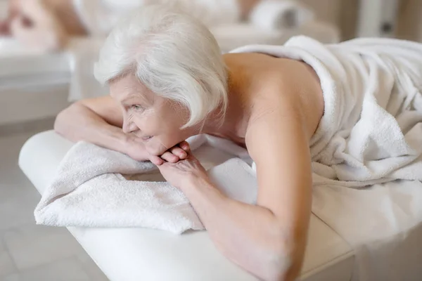 Senior woman lying on na couch in a spa salon — ストック写真