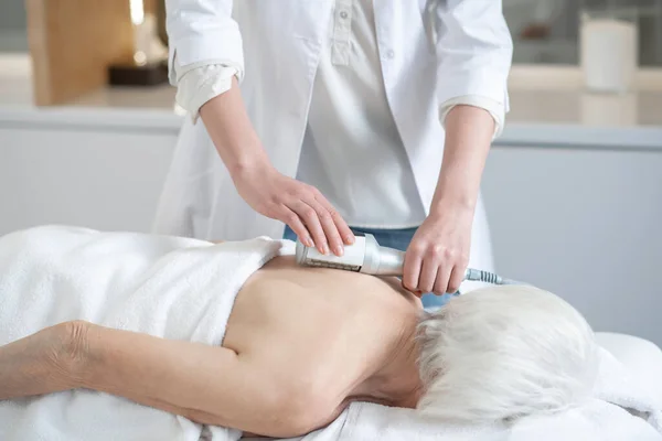 Μασάζ θεραπευτής κάνει πίσω διαδικασίες μασάζ σε μια γκρίζα μαλλιά γυναίκα — Φωτογραφία Αρχείου